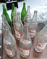 Photo showing 12 vintage Leominster Home Bottling soda bottles, 8 clear and 4 green bottles, labeled 'Home Beverages'.