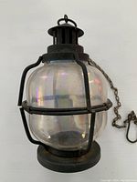 Front view of the antique luminous hanging lantern showing its glass globe and metal protective cage.
