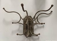 Front view of the antique folding wall coat hook showing multiple curved hooks with rounded ends and the mounting plate on the back.