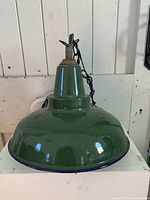 Front view of a green enamel industrial hanging light fixture showing shape, color and chain details.