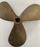 Full top view of three-blade bronze propeller on white background.