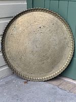 Full view of the large round brass tray showing its size, scalloped rim and overall engraved surface.