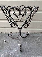 Full view of vintage twisted metal rope coil flower pot stand showing basket shape and curled feet