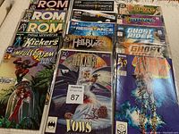 Overview photo of all 15 comics, showing front covers and titles including ROM, The Resistance, Dragonlance, Ghost Rider, Batman Dark Knight, Iron Man, Moon Knight, Impulse Shazam Double Shot