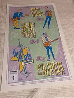 Concert poster laid flat on light surface showing colorful illustrations of musicians and text for June 1999 concerts at The Tower Theater Philadelphia.