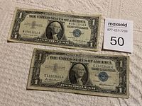Two United States one dollar silver certificate bills showing front sides with George Washington portrait, serial numbers, and treasury seals visible.