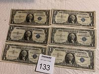 Top view of all six one dollar silver certificate bills arranged in two rows showing serial numbers and front design