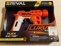 Photo showing boxed Nerf Rival Curve Shot Flex XXI-100 blaster toy gun with orange and white plastic build, black trigger, firing 5 high-impact rounds.