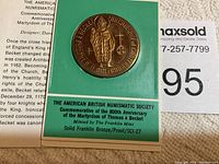 Medal displayed on green backing card displaying text about the American British Numismatic Society, commemorative occasion, and detail about the medal being minted by The Franklin Mint in solid bronze, proof finish.