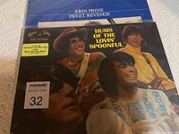 Two vinyl albums stacked, John Prine's Sweet Revenge partially visible behind Lovin' Spoonful's Hums of the Lovin' Spoonful.