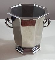 Front view of octagonal stainless steel ice bucket with dual handles and stepped base.