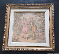 Framed tapestry showing full piece with ornate wood frame and white mat around the needlepoint artwork featuring a Victorian dancing couple.