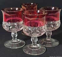 Front angle view showing the four vintage goblets with ruby flash tops and clear thumbprint textured bases.