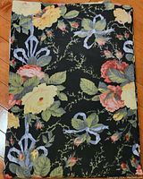Photograph showing folded fabric panel with detailed view of floral pattern on black background.