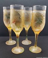 Photo of 4 vintage MCM art glass goblets with abstract marbled coloration and gold bands near rims