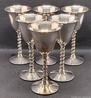 Front view of the six silver-tone goblets showing twisted grapevine stems and rounded bowls.