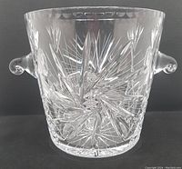 Clear crystal ice bucket with intricate pinwheel cut pattern front view showing one handle and detailed pattern.