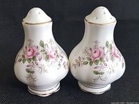 Front view of pair of Royal Albert Lavender Rose patterned bone china salt and pepper shakers showing pink rose floral design and gold trim.