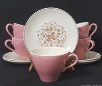Front view of stacked pink tea cups and a saucer showing the floral design