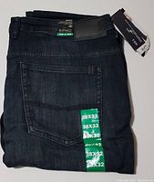 Folded jeans showing back pockets, leather brand patch, and size stickers 38x32.