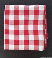 Folded red and white gingham check tablecloth showing overall pattern and fabric texture.