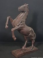 Front-side view of the brown cast iron rearing horse figurine showing the raised front legs and base.