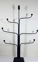 Full view of the black wrought iron hat stand with six arms and an owl finial at the top.