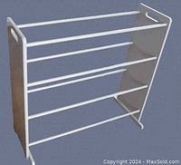 Front angled view of the white metal 4-shelf shoe rack showing structure and side handles.
