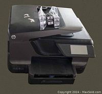 Front-left angled view of the HP Officejet Pro 8600 Plus e-All-in-One printer showing the touchscreen control panel and open paper output tray with two 950XL black ink cartridges placed on top.