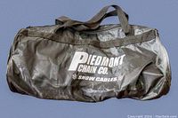 Black soft carrying bag with branding 'Piedmont Chain Co. Snow Cables' showing storage container for tire chains.