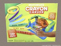 Photo of the Crayola Motorized Crayon Carver in original box showing device with sample carved crayons and colorful design.