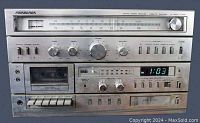 Front view of the Soundesign stereo receiver showing the AM-FM tuner scale, cassette tape deck, 8-track player buttons, volume and tuning knobs, and green LED digital clock.