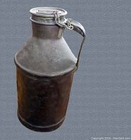 Front and side view of the vintage metal milk jug with hinged lid and handle, showing patina and rustic finish.