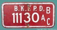 Front view of a vintage red fire protection district license plate featuring white embossed text and number '11130AC'.