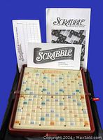 Scrabble playing board open with score sheets, rules, and source book displayed inside case