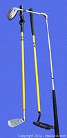 Photo showing three vintage practice golf clubs with yellow shafts, black grips, and different club heads against blue background.