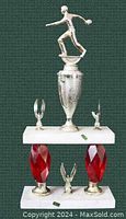 Full view of vintage bowling trophy on white marble base with two smaller winged figures and textured silver-tone cup, plus alternate base with red crystal-like pendants.