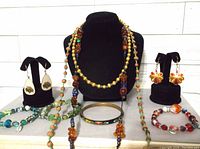 Photo showing entire jewelry lot with 3 necklaces, 2 bracelets, and 4 pairs of earrings on display stands