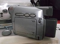 Side view of Canon ZR200 camcorder showing control buttons and model information, with Canon soft carrying case visible underneath.