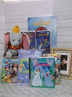 Wide shot of Disney lot showing Dumbo plush, VHS tapes, and framed items.