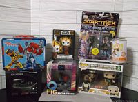 All 7 items displayed grouped on shelf, showing mostly unopened boxes and packaging; lunch box and soda can figure opened