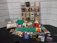 Photo showing a wide assortment of vintage matchbooks in a standing rack and loose in front, including branded hotel and casino matchbooks.