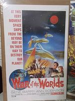 Color movie poster for War of the Worlds showing spaceships and explosion, sealed in plastic on board.