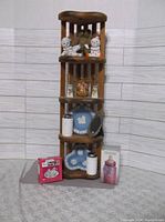Full view of wooden shelf with assorted knickknacks including ceramic dog figurines, decorative plates, glass jars, small mirror, collectible box, and boxed tea party set.