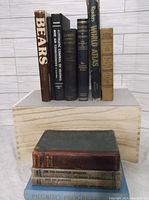 Front view of vintage books standing upright on a wooden box with one laying flat in front.