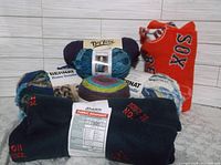 Full lot of yarn skeins and fabric remnants showing Boston Red Sox fleece pieces and Bernat yarns.