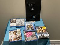 Seven DVD cases arranged on a blue tablecloth. Titles visible include Skyfall, Interstellar, Burnt, Fast & Furious 5, Fight Club, World Trade Center, The Boat That Rocked. Price stickers seen on some cases.