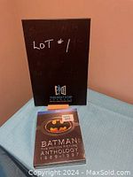 Photo of the same unopened Blu-ray set from a distance showing the packaging, placed next to a black folder with white and blue text in the background.