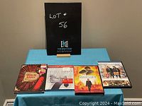 Photo shows all 4 DVDs with Moulin Rouge!, City of Ghosts, In the Name of the King, and The Family Stone titles clearly visible, displayed on a small blue table.
