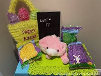 Easter grass bags, yellow Happy Easter grass bag, pink rabbit hat, and green lace placemats on blue tablecloth